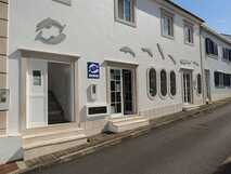 Weiße Fassade der Residencial Acquamarina mit Delfin-Dekor, ovalen Fenstern und Eingangstüren direkt an einer ruhigen Straße