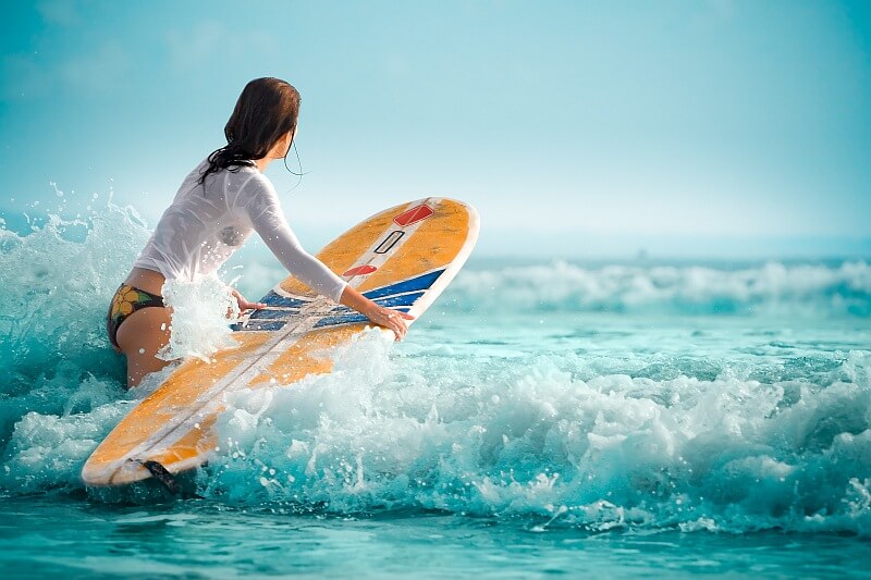Surferin geht mit Brett ins Wasser auf Boa Vista, Kapverden – friedlicher Start in einen aktiven Urlaubstag.