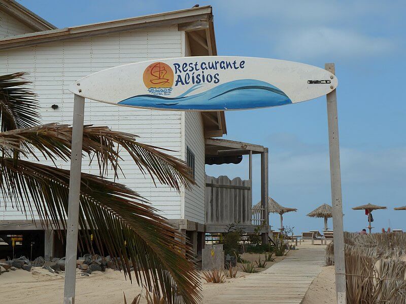 Restaurant mit Surfbrett-Schild am Strand auf den Kapverden – Treffpunkt für Surfer und Sonnenhungrige.